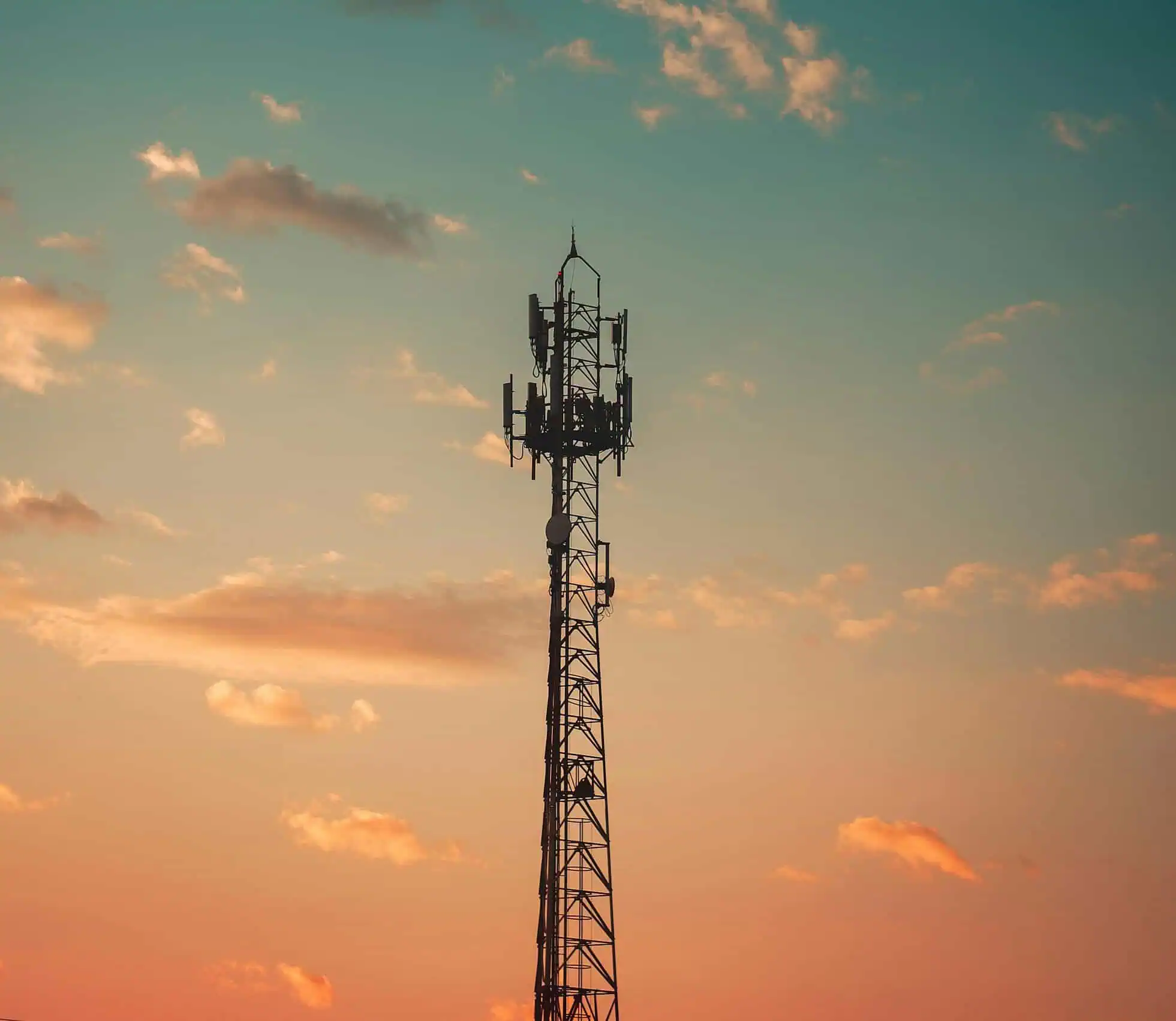 A communication tower silhouetted against a colorful sunset sky in Cruzeiro, Brazil.