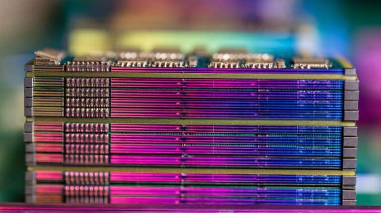 Stacked computer RAM modules with visible gold contact points and colored light reflections on surfaces.