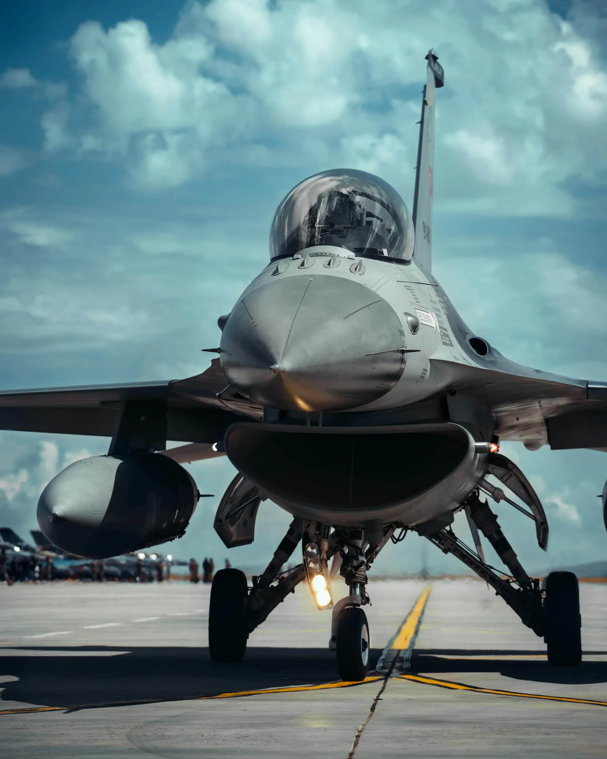 Front view of a fighter jet on a runway under a bright blue sky, showcasing military aviation.