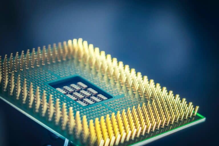 Close-up of a computer processor chip with gold pins against a blurred blue background.