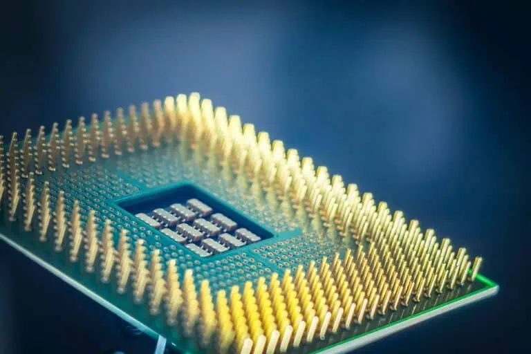 Close-up of a computer processor chip with gold pins against a blurred blue background.